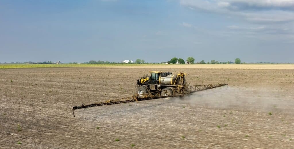 Agricultural sprayer applying herbicide in a large open field for weed control, part of the Weed Science Society of America activities.